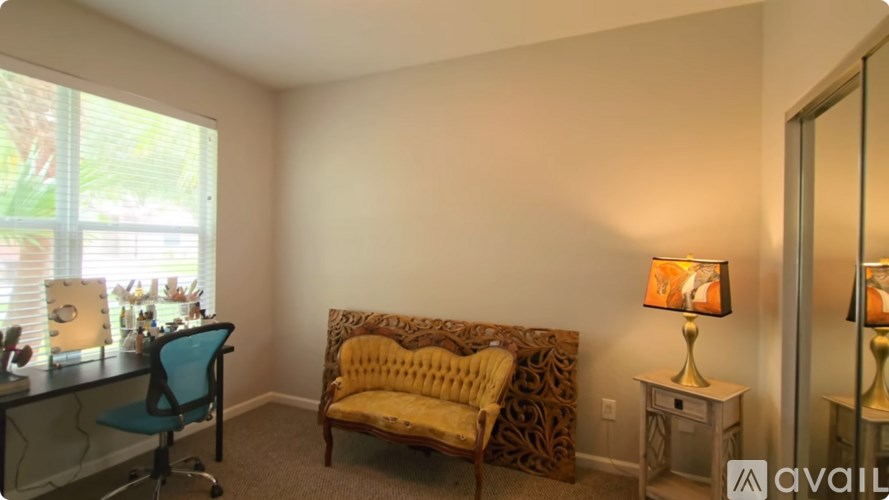 A room with a yellow chair and a desk with a lamp on it.