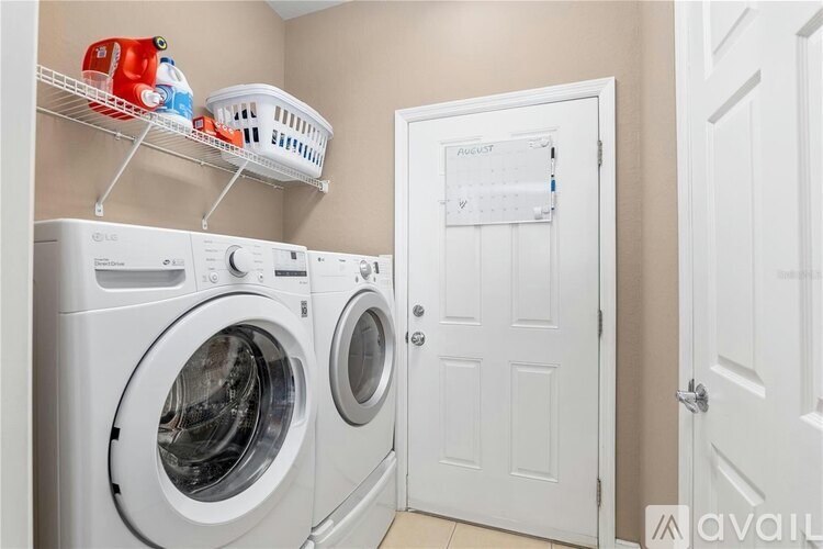 A laundry room with a washer and dryer and a basket on top of the washer.
