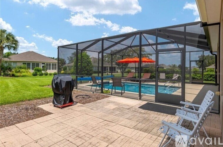 A patio with a pool and a black umbrella.