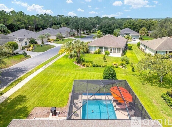A swimming pool with a sun shade is surrounded by houses.