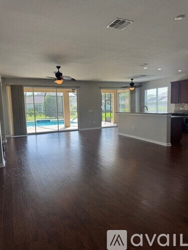 A spacious room with wooden floors and a ceiling fan.