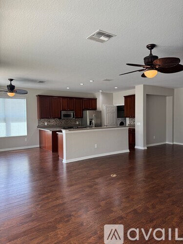 A spacious kitchen and living room with wood flooring and a ceiling fan.