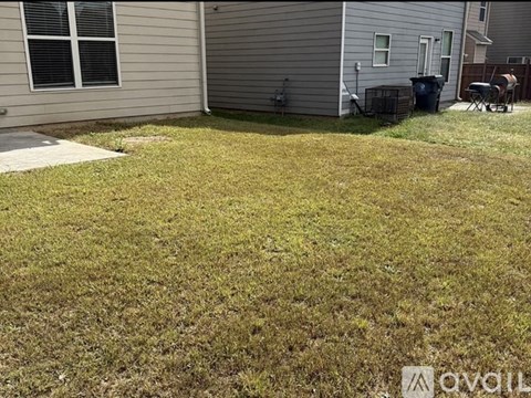 A backyard with a lawn and a house in the background.