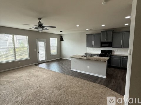 A spacious living room with a kitchen area in the background.