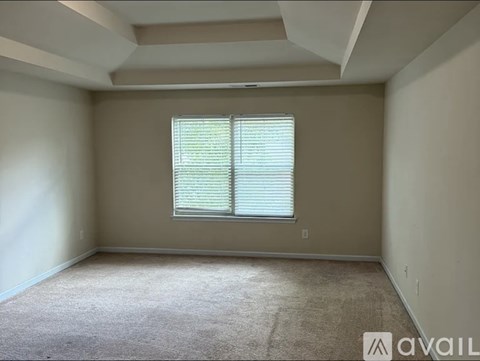 A room with a carpeted floor and a window with blinds.