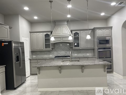 A modern kitchen with a granite countertop and stainless steel appliances.