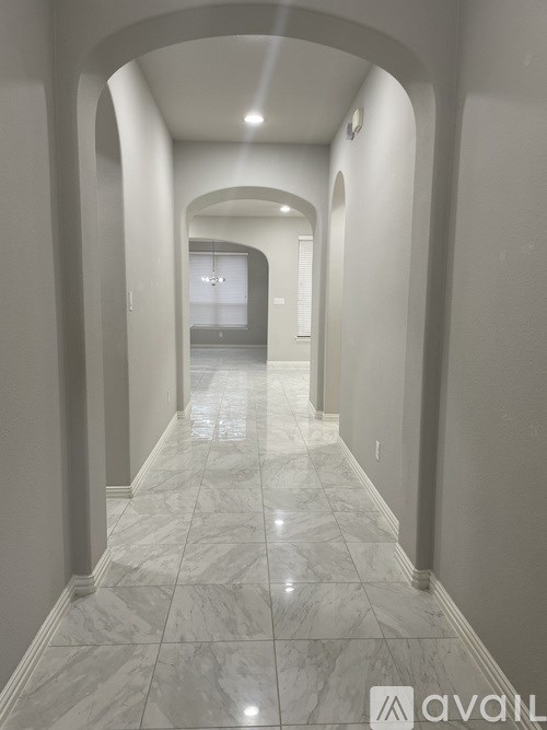 A long hallway with marble floors and arched columns.