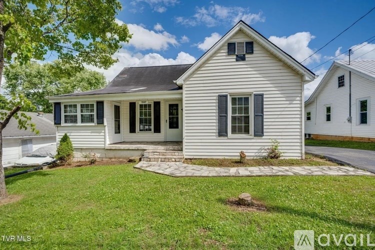 A white house with a black roof and a small front yard.