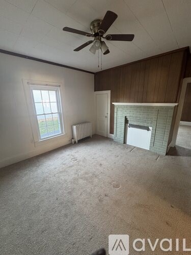 A room with a ceiling fan, a window, and a fireplace.