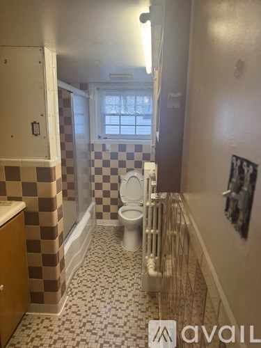 A bathroom with a checkered tile wall and a white toilet.