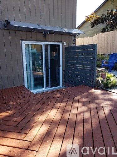 A wooden deck with a sliding glass door and a blue chair.