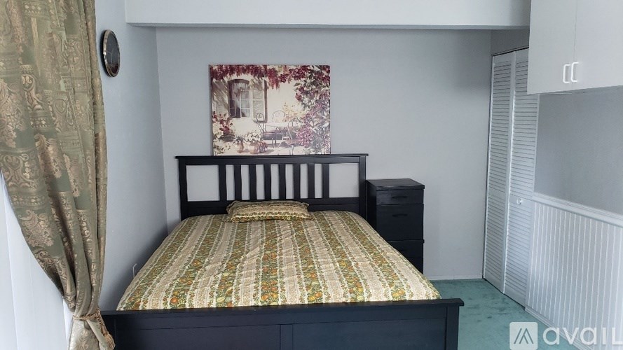 A bedroom with a bed, a dresser, and a painting on the wall.