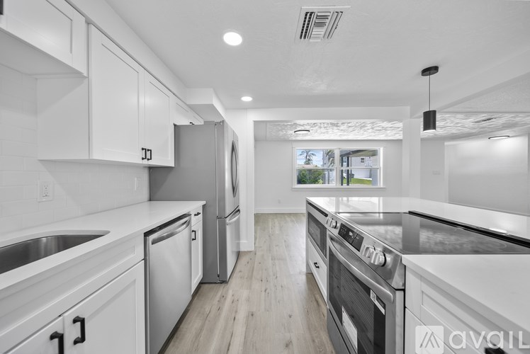A modern kitchen with white cabinets and stainless steel appliances.