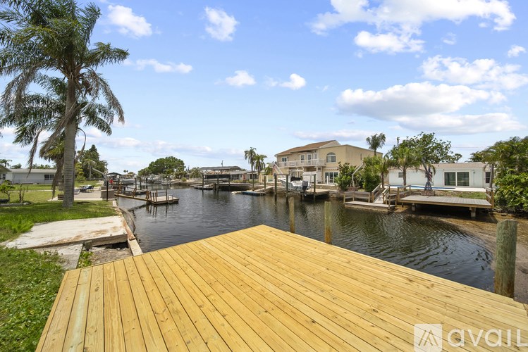 A wooden deck overlooks a body of water with houses and trees in the background.