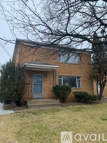 A house with a front yard and a tree in front of it.