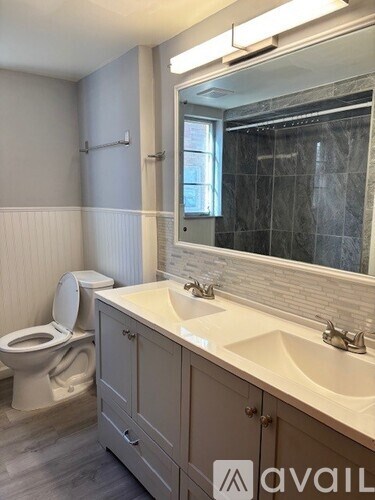 A bathroom with a toilet, sink, and mirror.