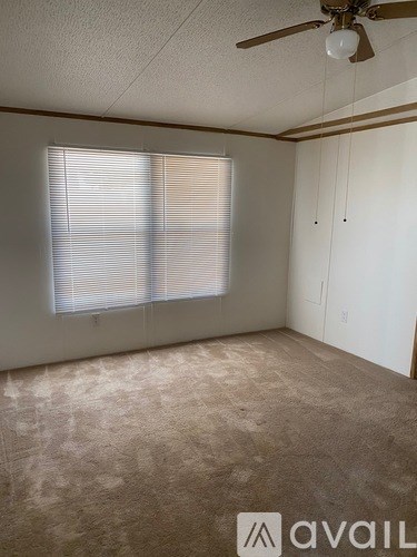 A room with a ceiling fan and a window with blinds.