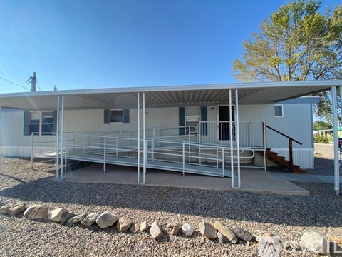 A metal building with a grey roof and a gravel area in front.