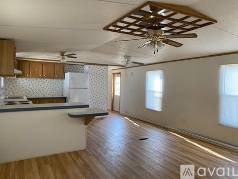 A kitchen with wooden floors and a ceiling fan.