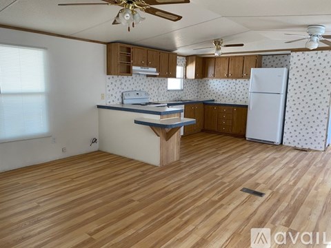 A kitchen with wooden floors and a ceiling fan.