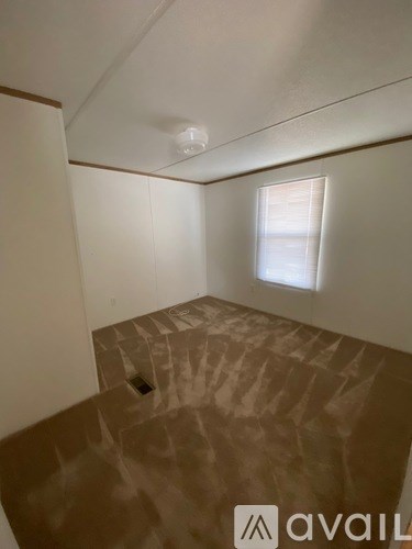 A room with a window and a brown floor.
