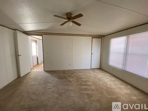 Empty room with a ceiling fan and carpeted floor.