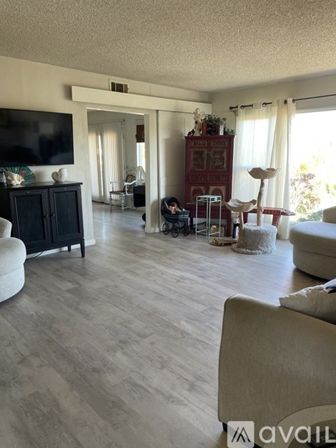 A living room with a television, a cabinet, a chair, a table, and a cat tree.