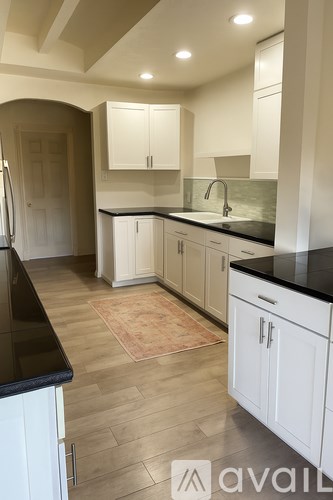 A kitchen with white cabinets and black countertops.