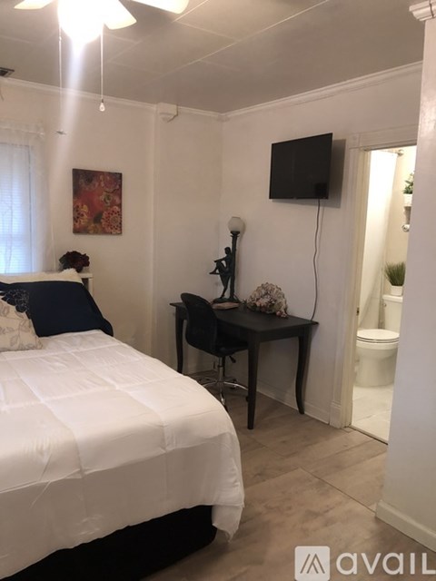 A bedroom with a bed, desk, and television.