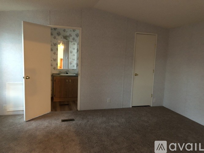 A room with a carpeted floor and two doors, one of which is open.