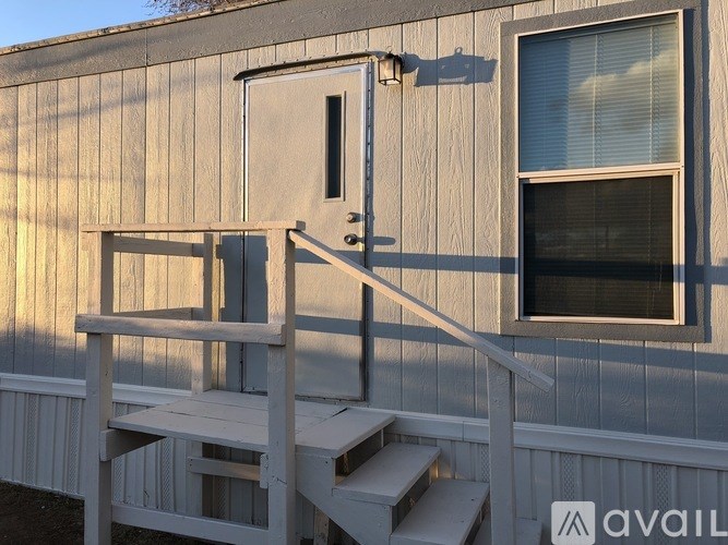 A wooden deck with a bench and a door is attached to a house.