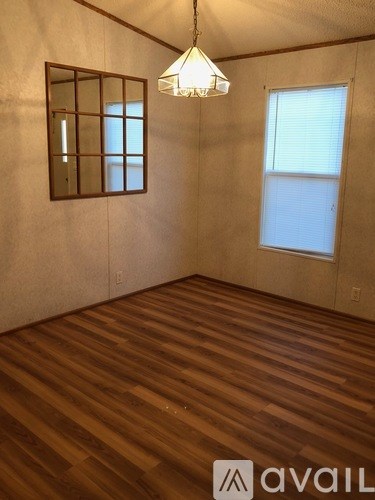 A room with wooden flooring and a window with blinds.