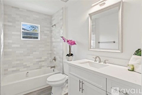 A white bathroom with a toilet, sink, and a framed picture on the wall.