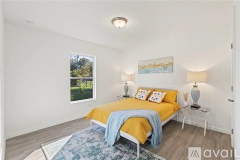 A bedroom with a bed, two lamps, and a painting on the wall.