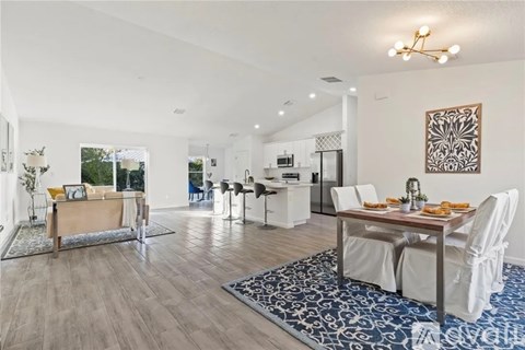 A dining room with a table set for two and a kitchen in the background.