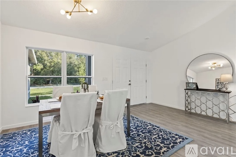 A dining room with a table set for two and a view of the backyard.