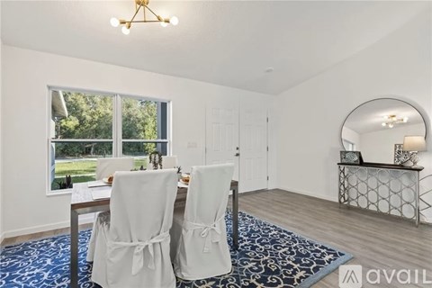 A dining room with a table set for two and a view of the backyard.