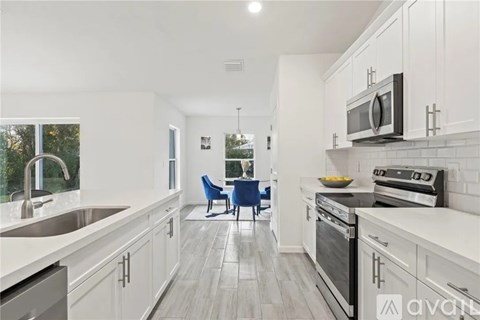 A modern kitchen with a blue chair and stainless steel appliances.