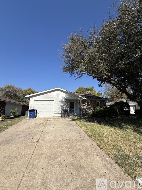 A house with a driveway and a tree in front.