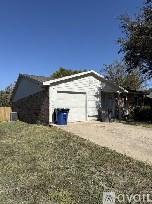 A house with a white garage door and a blue trash bin.