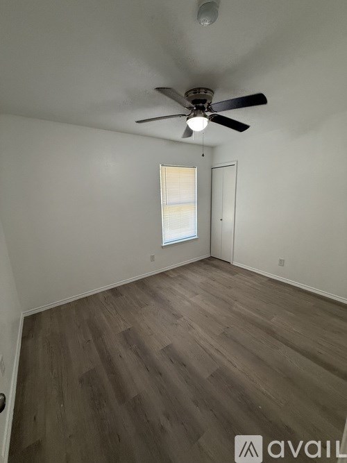 A room with a ceiling fan and wooden flooring.
