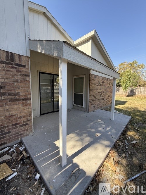 A house under construction with a white porch and a brick wall.