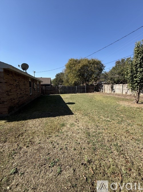 A backyard with a fence and a house in the background.