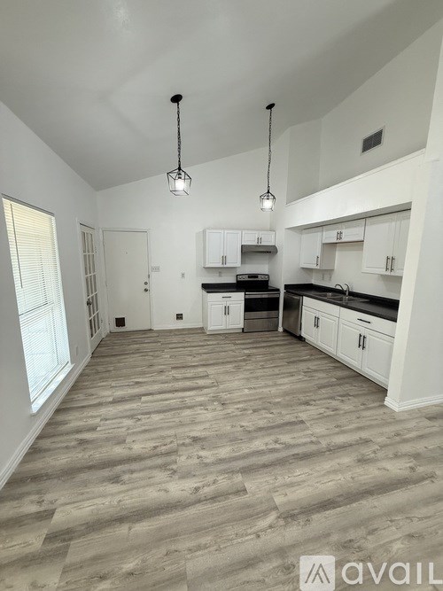 A spacious kitchen with white cabinets and a wooden floor.