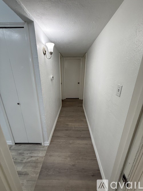 A long hallway with white walls and wood flooring.