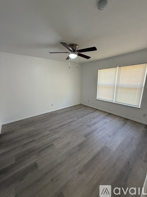 A room with a ceiling fan and wooden flooring.