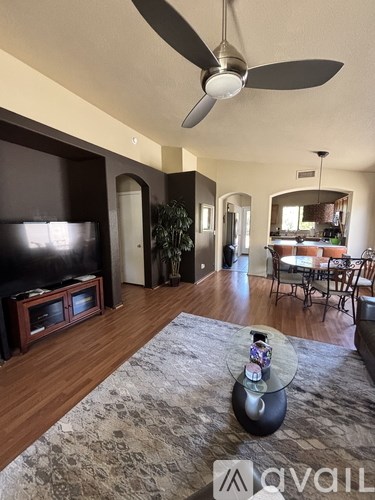 A living room with a television, a fan, and a rug.