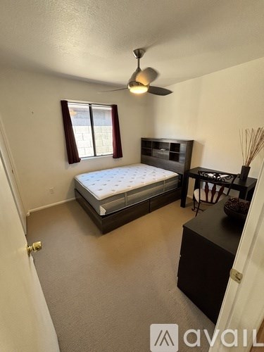 A bedroom with a bed, dresser, and ceiling fan.
