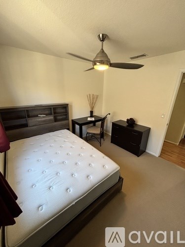 A bedroom with a bed, nightstand, and a fan.