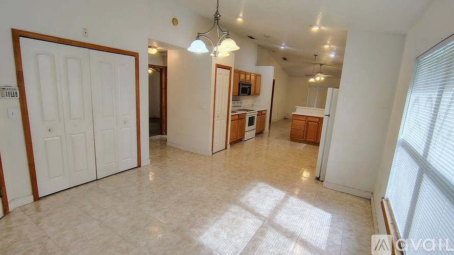 A spacious living room with a kitchen in the background.